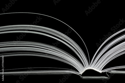 A black and white image of open book. Close-up image of double-page spread on black background. Concept of gaining knowledge, learning, typography, passion for reading