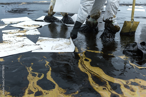 Workers remove and clean up crude oil spilled with absorbent paper