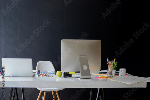 Stylish workspace with desktop and laptop computer, office supplies, houseplant and books at home or studio. Blank screen for graphics display montage.