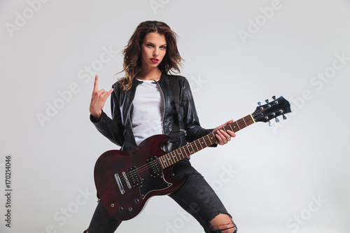 cool woman guitarist making a rock and roll hand sign