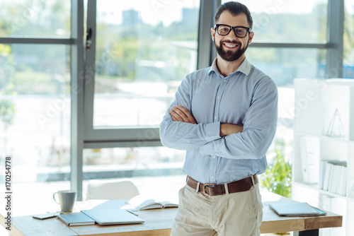 Cheerful bearded man posing in his new office