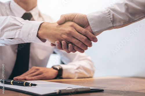 Estate broker agent and customer shaking hands after signing contract documents for realty purchase mortgage loan approval