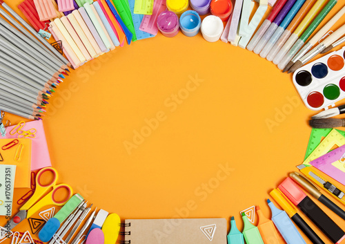 School supplies frame on orange background.