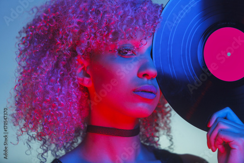 portrait of a disco woman holding a vinyl with eighties music and neon light
