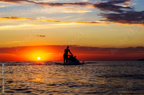 silhouette of a man on a jet ski in the sun
