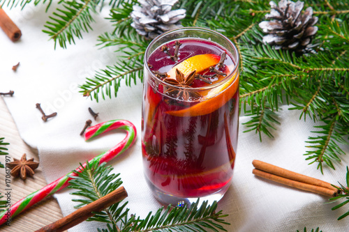Świąteczne grzane wino z cynamonem i goździkami, otoczone ozdobami na Boże Narodzenie. 