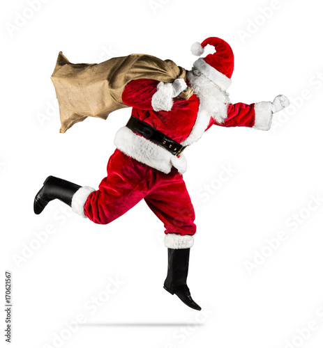 red traditional santa claus with bag of christmas gifts presents running jumping isolated on white background / Weihnachtsmann in eile rennt mit Sack voll Geschenke isoliert auf hintergrund weiß