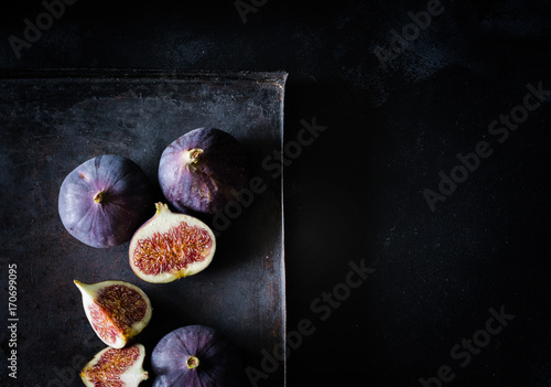 Feigen als ganze Frucht und im Anschnitt von oben auf schwarzem Untergrund bei Tageslicht fotografiert