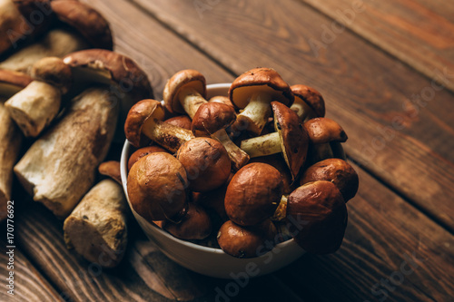 Mushrooms in plate and on kitchen wooden table