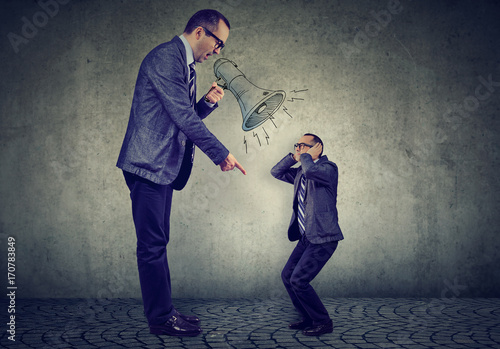 Angry mature business man boss screaming at small himself in megaphone