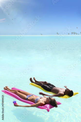 Young couple relaxing on air mattress at crystal clear water ocean