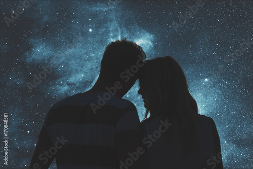 Silhouettes of a young couple under the starry sky. 