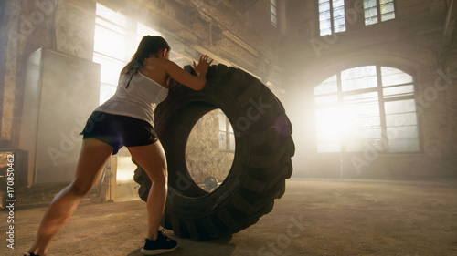 Fit Athletic Woman Lifts Tire as Part of Her Cross Fitness/ Bodybuilding Training.