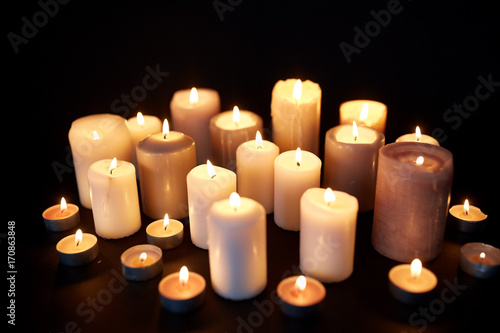 candles burning in darkness over black background