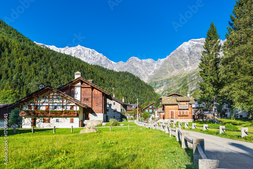 Picturesque and characteristic alpine village, Italy. Macugnaga (Staffa), little touristic village with wooden and stone houses at the foot of the east wall of Monte Rosa, on a beautiful summer day