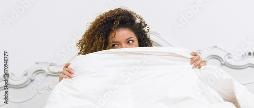 Beautiful woman hiding behind blanket with rascal look, letterbox