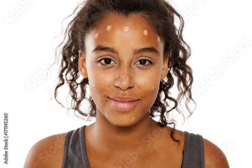 a young dark skinned woman spots of liqiud foundation on her face
