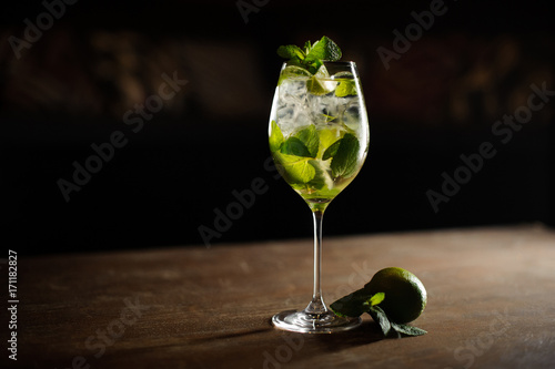 Mojito cocktail with lime and mint in highball glass on a dark stone background
