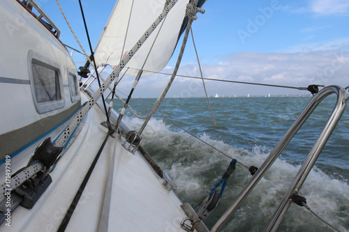 Sail boat gliding in open sea during a race in The Solent near Isle of Wight, England