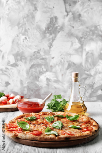 Delicious pizza with tomatoes and fresh basil on kitchen table