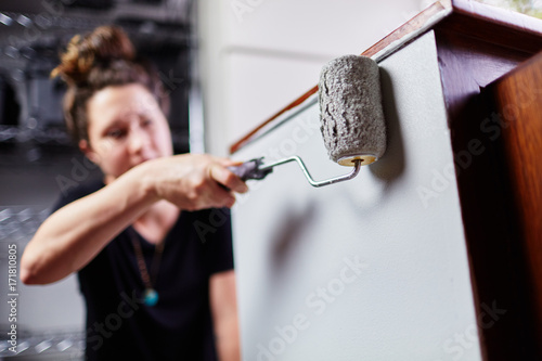 woman painting a cabinet with brush