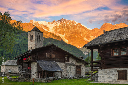 Spectacular east wall of Monte Rosa at dawn from the picturesque and characteristic alpine village of Macugnaga (Staffa - Dorf) with old-fashioned houses and the old church, Italy