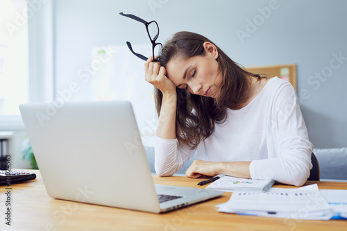 tired young office worker at desk while trying to work in modern office