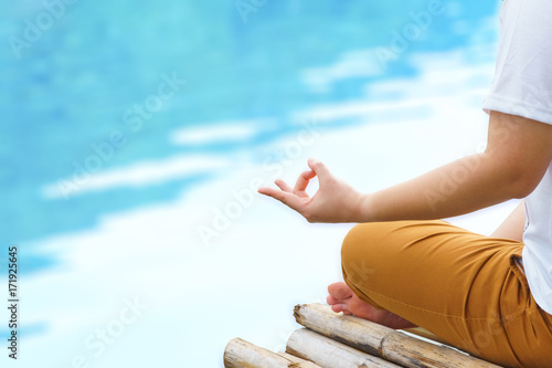 hands of woman meditating on a yoga pose on the blue river