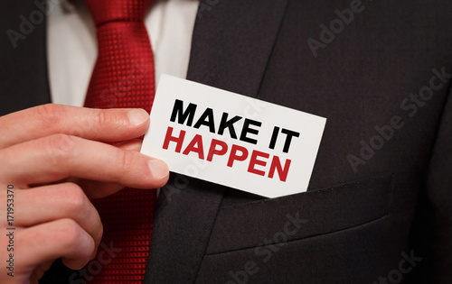 Businessman putting a card with text Make it happen in the pocket