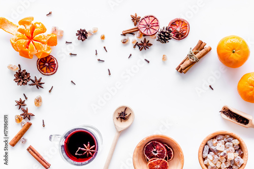 Hot mulled wine or grog cooking for new year celebration with oranges and spices ingredients on white background flat lay