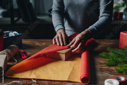 woman wrapping book as christmas gift