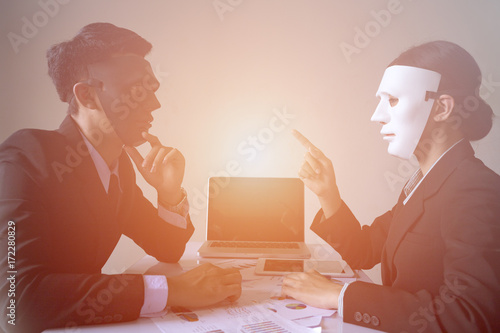 Businessman and businesswoman with mask in office hypocrisy concept