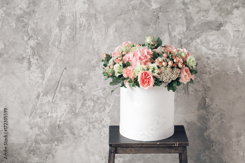 Beautiful tender bouquet of flowers in white box on gray ackground with space for text