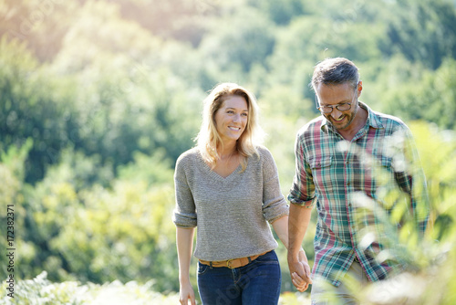 Happy mature couple walking in countryside on sunny day