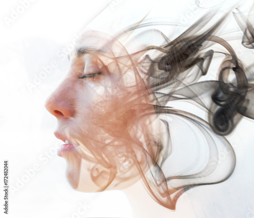 Double exposure portrait of a young fair-skinned woman and a smoky texture dissolving into her facial features