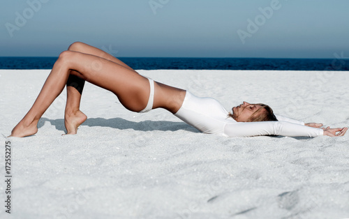 Beautiful tanned woman in a white swimsuit on the beach.