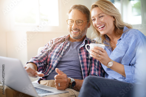 Mature couple connected on internet with laptop