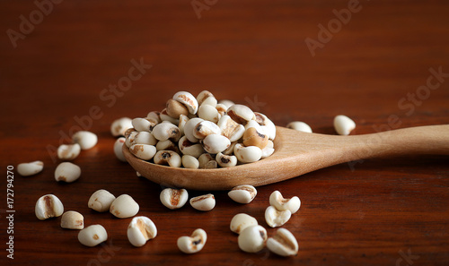 job's Tears in wooden spoon on rustic wood background.