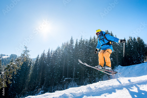 Professional skier jumping in the air while skiing in the mountains blue sky on the background copyspace sunlight extreme freeride adrenaline sportsman activity enjoyment at the winter ski resort