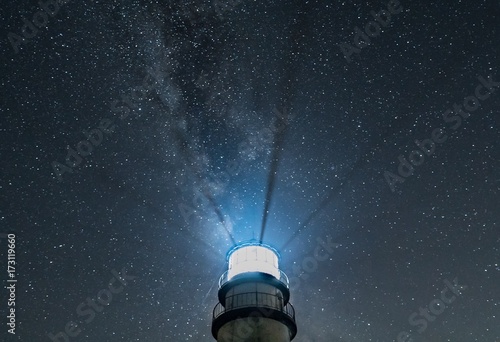 Lighthouse beams at night with starry sky and Milky Way 