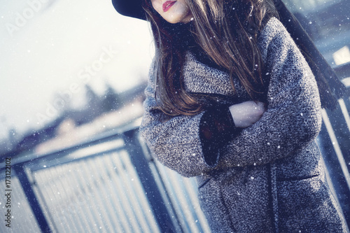 Girl in a freezing snow storm. Headless portrait. Red lips showing. Wearing hat and coat.