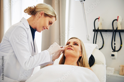 Doctor doing botox injections on a mature woman's face