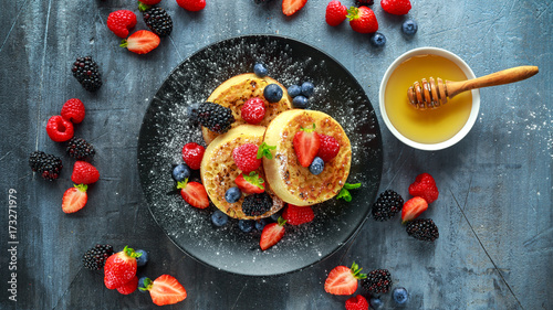 British Crumpets breakfast with blueberries, strawberries, blackberries, raspberries drizzled with icing sugar