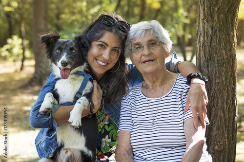 happy senior woman with her granddaughter and their dog in the park