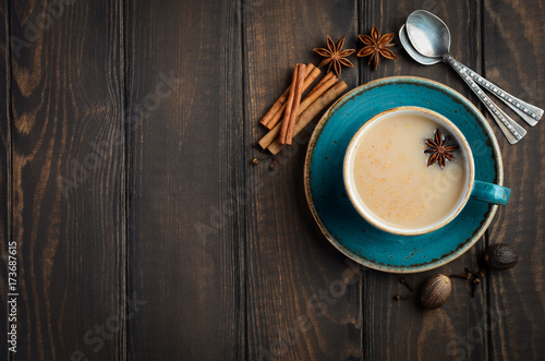 Indian masala chai tea. Spiced tea with milk on dark wooden background.