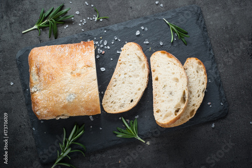 Italian ciabatta bread on black slate with herbs and olives.