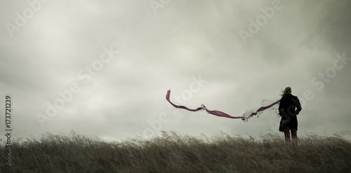 Woman standing alone in harsh weather with dramatic sky