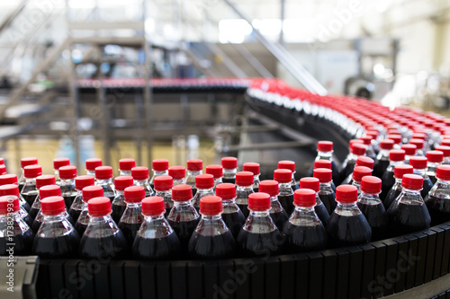 Bottling factory - Black juice or soft drink bottling line for processing and bottling juice into bottles. Selective focus. 