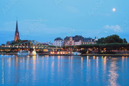 Evening river, bridge, embankment and church. Frankfurt am Main, Germany