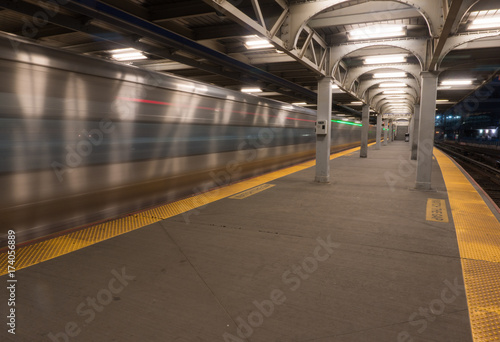 Long exposure motion blur of railroad train passing station platform at fast high speed